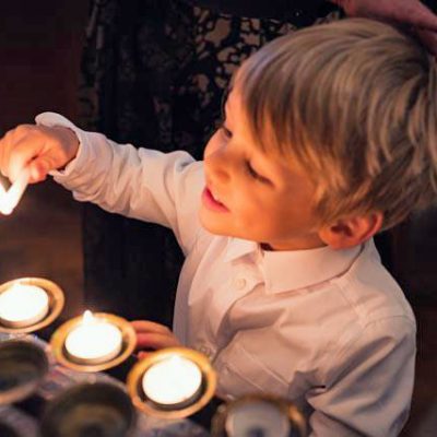 A boy lights a candle after being baptised at St Edmund's
