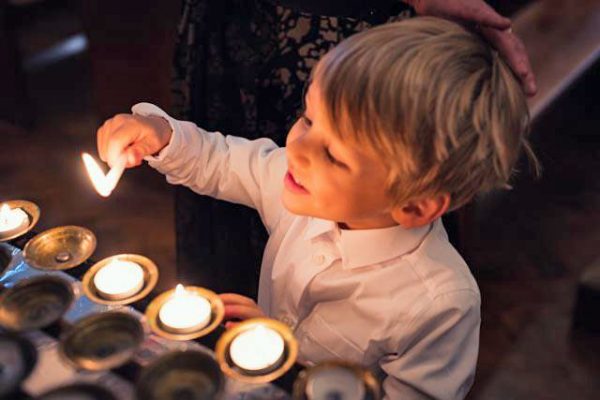 A boy lights a candle after being baptised at St Edmund's